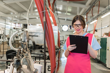 young woman controlling automated production of textile thread and cotton spinning