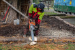 © Claudine - Young lumberman is sawing with a motor saw and gasoline in background a wood trunk on a playground in rainy day outdoor.