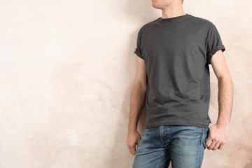 Wall Mural - Men in blank grey t-shirt against color background, space for text