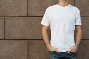 Wall Mural - Men in blank white t-shirt against building, space for text