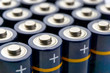 Batteries in rows. Close-up or macro of blue alkaline AA batteries with yellow stripes and plus sign on the positive pole. Image with selective focus and isolated on top for copy space.