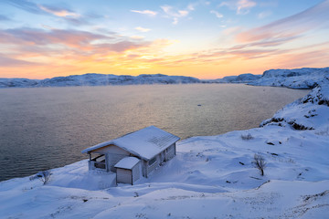 A wooden house, Barents sea at sunrise in Teriberka, Murmansk Region, Kola Peninsula. Russia