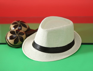 Panama hat with maracas in a green and red background.