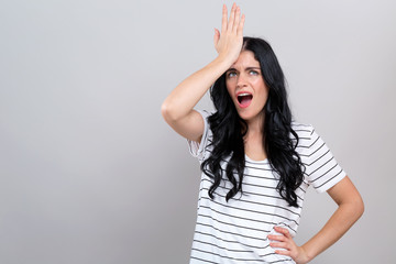 Young woman making a mistake on a gray background