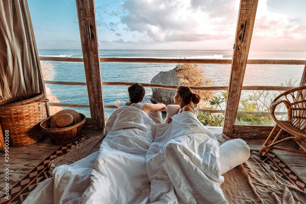 Couple enjoying morning vacations on tropical beach bungalow looking ocean view Relaxing holiday at Uluwatu Bali ,Indonesia - obrazy, fototapety, plakaty 