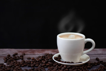 White coffee mugs on a wooden table with coffee beans on the floor.