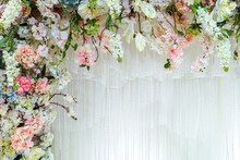 Background Of White Curtains Are Adorned With Beautiful Artificial Flowers With Copy Space.