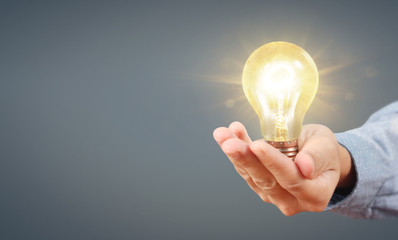 Hand of holding illuminated light bulb, innovation inspiration concept