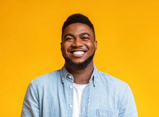portrait of cheerful bearded black man over yellow background