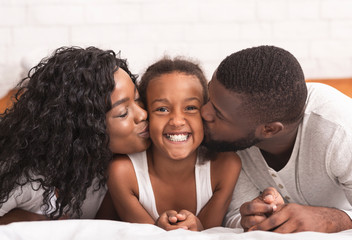 Wall Mural - Loving black parents kissing cheeks of their happy little daughter