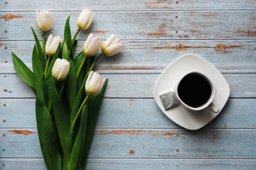 Wall Mural - White bouquet of tulips on a wooden blue background with a Cup of coffee