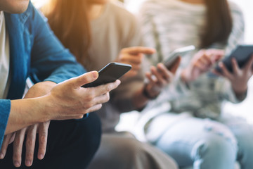 group of people using and looking at mobile phone and tablet pc while sitting together