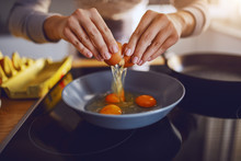 Close Up Of Caucasian Woman Breaking Egg And Making Sunny Side Up Eggs. Domestic Kitchen Interior. Breakfast Preparation.