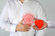 © kittyfly - man in a white shirt holds on to his chest, a red circle, a symbol of throbbing pain, a doctor with red heart model, the concept of health problems, heart disease, surgery, organ transplantation