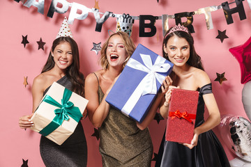 Sticker - Image of joyful party girls in fancy dresses holding birthday gift boxes