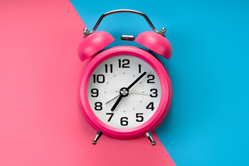 pink rustic alarm clock on pink blue background