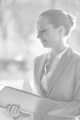 Wall Mural - Confident young businesswoman standing while reading document at office