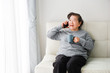 © chayathon2000 - Asian senior woman mother talking with mobile  phone and drinking coffee in living room
