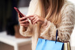© Kalim - Adult women shopping for clothes in boutique in autumn and using smartphone