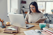 © gstockstudio - Beautiful young woman in casual clothing using laptop and smiling while working indoors