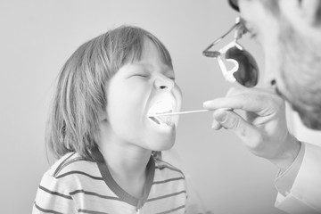 Doctor checking tonsils of patient at hospital