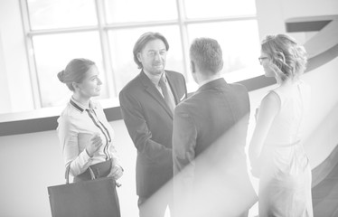 Wall Mural - Businessmen greeting while standing with colleagues at reception lobby in office