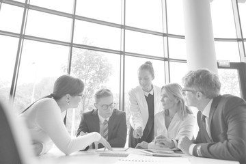 Wall Mural - Business colleagues discussing while sitting at table in office lobby during meeting