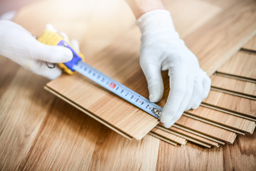 Man installing laminated wooden floors, Professional floor work measuring in new house.