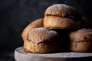 A stack of buns filled with chocolate sprinkles placed on a wooden board with dark background