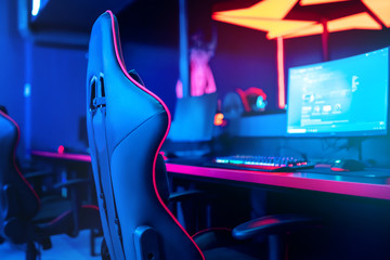 Blurred background computer pc, keyboard armchair, blue and red lights. Concept online eSports arena for gamer playing tournaments