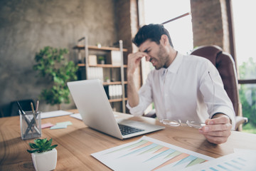 Profile side photo of exhausted middle eastern entrepreneur have lots work on computer touch his nose hold glasses feel burnout sit desk in loft wearing white shirt