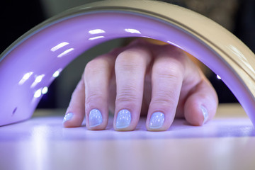 Close-up of the process of drying nails with gel polish in an ultraviolet lamp. Manicure in a beauty salon for female hands