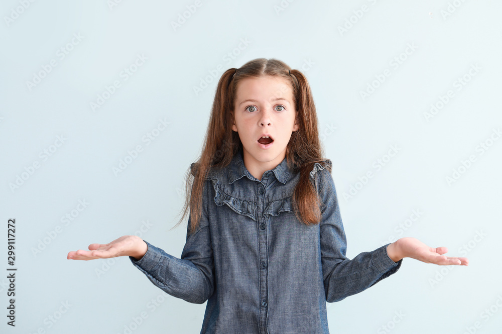 Shocked little girl on light background