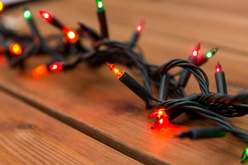 christmas, holidays and illumination concept - electric garland lights on wooden background