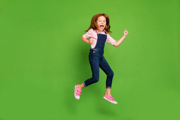 Canvas Print - Full length photo of cheerful pretty little schoolchild jumping high rejoicing summer holidays start wear casual denim overall pink shirt isolated green background