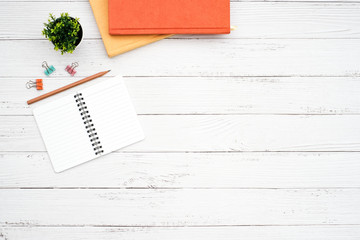 Wall Mural - Work space black to school desktop concept on white wooden table desk with blank notepad and stack of book , glass, pencil, green plant and paper clip, flat lay, Top view with copy space