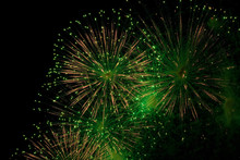 Green And Golden Sparks Of Fireworks Exploding In The Sky And Smoke From The Charges