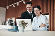 © Flamingo Images - Smiling businesspeople standing in an office working on a laptop