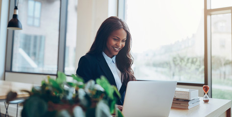 Wall Mural - Smiling African American businesswoman using a laptop at her des