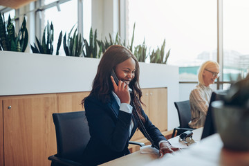 Laughing African American businesswoman talking on an office pho