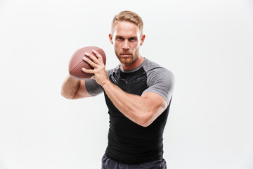 Wall Mural - Focused young fit sportsman holding rugby ball isolated