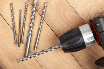 Close up drilling machine, screwdriver with drills on wooden table . Prepared for drilling holes in concrete