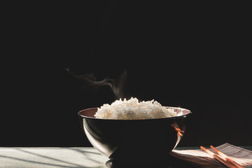 Jasmine rice in a bowl and on a old wooden table and black background, Morning nature light by the window, Selective focus, Vintage style..