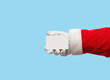 © eggeeggjiew - Santa Claus hand holding plastic credit card over isolated blue background.