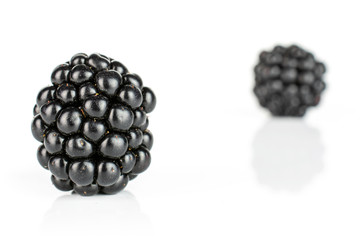 Group of two whole fresh black blackberry isolated on white background