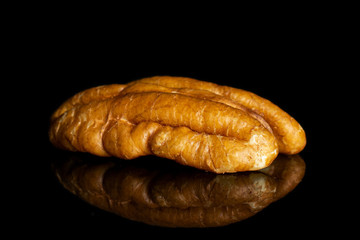 One whole dry brown pecan nut isolated on black glass