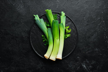 Raw green leek on black background. Vegetables for healthy eating. Top view. Free copy space.