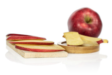 Wall Mural - One whole lot of slices of fresh apple red delicious on wooden cutting board on round bamboo coaster isolated on white background