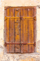 A very old double door in the brick wall. The door has peeling yellow paint and two padlocks.