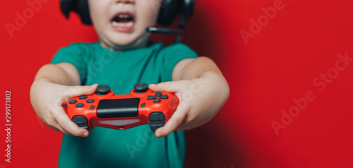 Fotografía small boy in headphones and joystick on red background